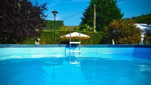 an umbrella and a chair in a swimming pool at Casa Madrazo con piscina y parrillas in Praves