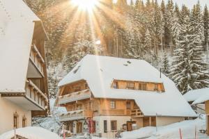 ein schneebedecktes Haus mit der Sonne im Hintergrund in der Unterkunft Holiday Apartements by Hotel Grüner Baum Feldberg in Feldberg