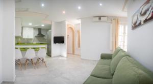 a living room with a green couch and a kitchen at Caminito del Falla I Ha Apartment in Cádiz