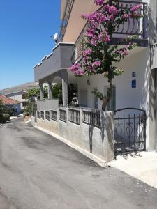a building with a fence and a tree with purple flowers at Apartment Luna in Trogir