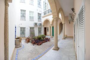 um pátio de um edifício com mesas e cadeiras em Caminito del Falla II Ha Apartment em Cádiz