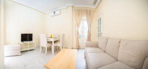 a white living room with a couch and a table at Caminito del Falla A Ha Apartment in Cádiz