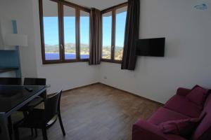 a living room with a purple couch and a table at Nuraghe Apartments in Teulada