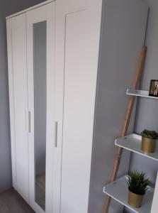 a white wardrobe in a room with shelves at Lovely place-apartament Oświęcim in Oświęcim