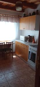 a kitchen with a stove and a table with chairs at Hegyi Nyaraló in Sátoraljaújhely