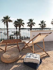 a hammock and a chair on a beach with palm trees at Casa Clementina Rooms vista mare in Porto Cesareo