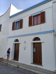 una mujer está parada fuera de un edificio blanco en Ca' margo, en Calasetta