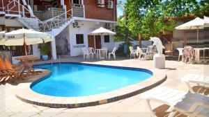 una piscina en un patio con sillas y mesas en Che Lagarto Hostel Porto de Galinhas en Porto De Galinhas