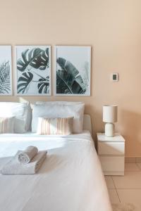 a bedroom with a white bed with three pictures on the wall at GuestReady - The Pastel Reflections in Dubai
