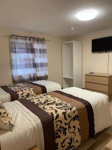 a hotel room with two beds and a television at Nights Inn in Slough