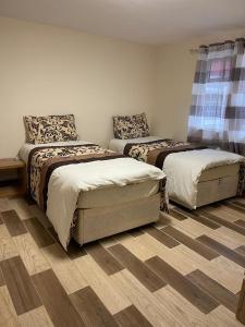 a bedroom with two beds and a wooden floor at Nights Inn in Slough