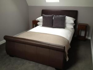 uma cama grande com uma cabeceira castanha e almofadas em Home Farm Apartments em Portree