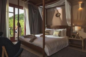 1 dormitorio con cama con dosel y una mujer de pie fuera en Rouista Tzoumerka Resort en Vourgareli