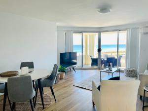 una sala de estar con mesa y sillas y el océano en Cottesloe Beach View Apartments #7 en Perth