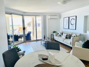 een woonkamer met een tafel en een bank bij Cottesloe Beach View Apartments #7 in Perth