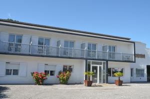 a white building with potted plants in front of it at Hôtel Land'Azur in Mimizan-Plage