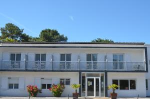 un edificio blanco con balcones y macetas en Hôtel Land'Azur en Mimizan-Plage