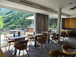 ein Restaurant mit Tischen und Stühlen und einem großen Fenster in der Unterkunft Hotel Zirbenhof in Hochfugen