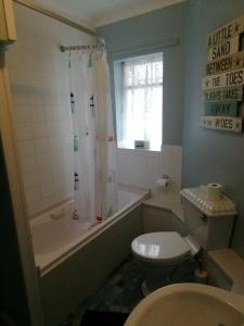 a bathroom with a toilet and a tub and a sink at Railway Cottage in Swanage