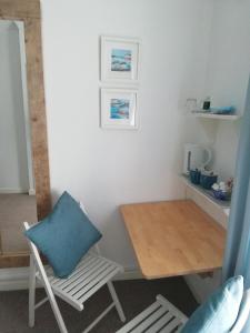 a table and a chair with a blue pillow in a room at Railway Cottage in Swanage