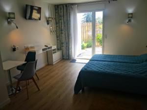 a bedroom with a bed and a desk and a window at Hotel L'Ancre d'or in Pénestin