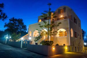 une maison avec un arbre devant elle la nuit dans l'établissement Niovi, à Fira