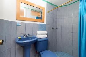 bagno con servizi igienici blu e lavandino di Hostal Rossy a Baños