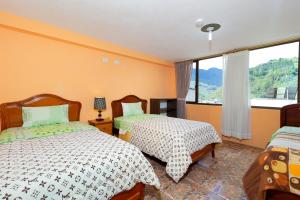 una camera da letto con due letti e una grande finestra di Hostal Rossy a Baños