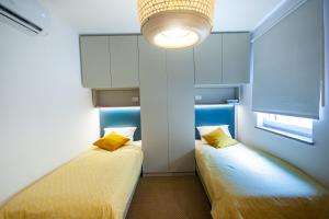 two beds in a small room with a light at Rainbow apartment, Koper in Koper