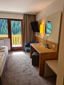 una camera d'albergo con scrivania, letto e finestra di Hotel Zirbenhof a Hochfugen