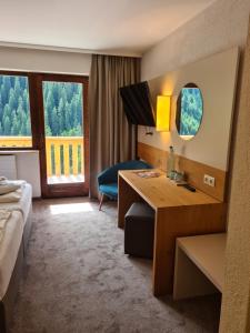 ein Hotelzimmer mit einem Schreibtisch, einem Bett und einem Fenster in der Unterkunft Hotel Zirbenhof in Hochfugen