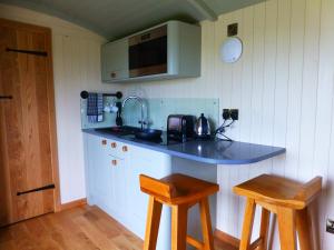 cocina con encimera con fregadero y 2 taburetes en Hay-on-Hye retreat, en Hay-on-Wye