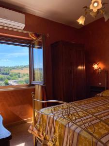Locanda del Borgo في تودي: غرفة نوم بسرير ونافذة كبيرة
