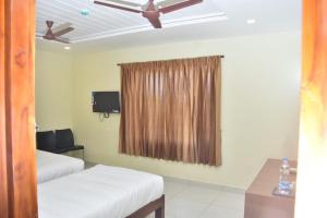 a room with two beds and a window with a ceiling fan at Le Arul Park in Karaikal