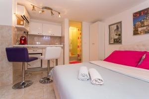 a bedroom with a large white bed and a kitchen at Modern and practical studio in the heart of Split in Split