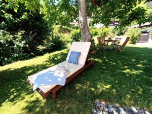 una silla sentada en la hierba bajo un árbol en Schwalbennest Velden en Velden am Wörthersee