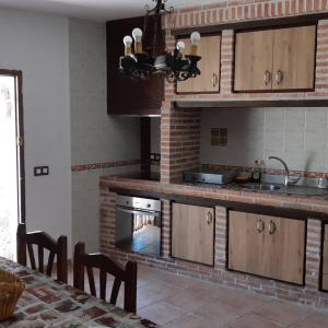 a kitchen with wooden cabinets and a brick wall at CASA CUEVA LOS HONORIOS in Cortes de Baza +20 photos