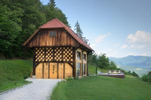 un pequeño edificio de madera en una colina con césped en Rustic retreat with pool počitnice na kozolcu, en Sevnica