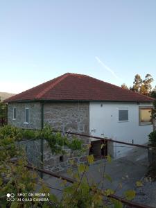 uma antiga casa de pedra com um telhado vermelho em Casa Cantinho dos Pais em Paredes de Coura