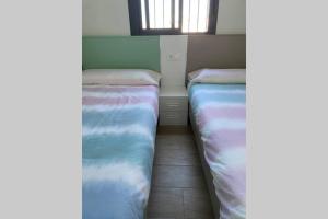 - 2 lits dans une petite chambre avec fenêtre dans l'établissement La Juli, Exclusivo chalet nuevo, de lujo, à Matalascañas