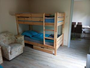 a bunk bed with a ladder and a chair in a room at Therapiescheune Egsdorf - Monteurwohnungen in Egsdorf +5 photos