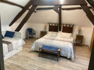 a attic bedroom with two beds and a blue chair at Le Jaonnet in Nabirat