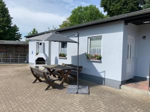 a picnic table with an umbrella next to a building at Ferienwohnung Römmer in Ströbeck