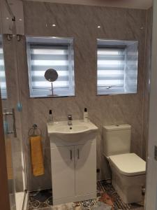 a bathroom with a sink and a toilet and two windows at Headwards Retreat in Hemsby