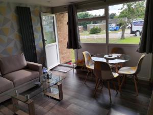 a living room with a couch and a table and chairs at 107 Headwards Retreat in Hemsby