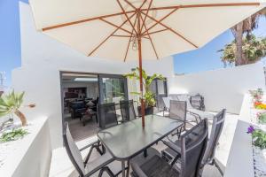 a dining room with a table and chairs and an umbrella at Apartamentos Temisa in Puerto del Carmen