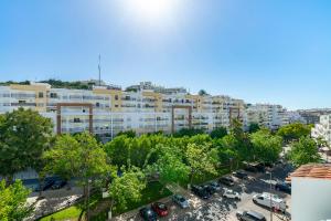 an apartment building with cars parked in a parking lot at Natural Grey Albufeira in Albufeira