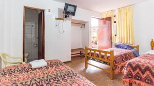 1 dormitorio con 2 camas y TV en la pared en Hostal Ñaña, en Huaraz