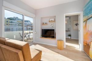 a living room with a couch and a large window at Natural Grey Albufeira in Albufeira