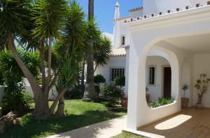 una casa blanca con palmeras en el patio en Villa a Sul, en Albufeira